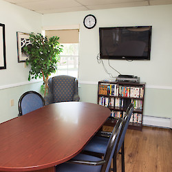 Small private meeting room with large table, TV and books at 60 West in Rocky Hill, CT
