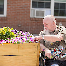 Resident participating in gardening, working in flower box in couryard of 60 West, Rocky Hill